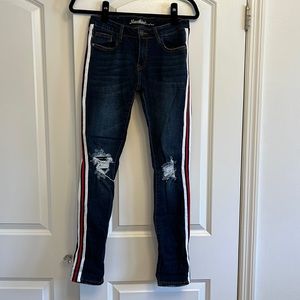 Dark blue jeans with rips by knees. Red, white & navy stripe detail along sides
